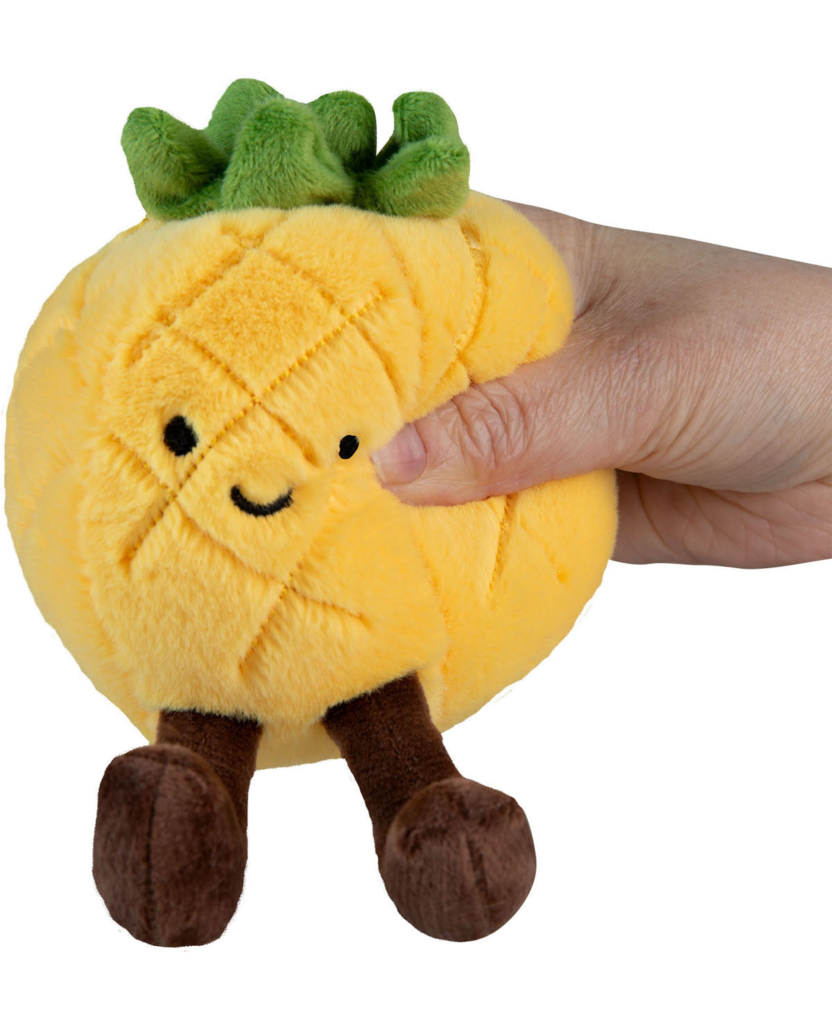 Plush pineapple toy held by a hand on a white background