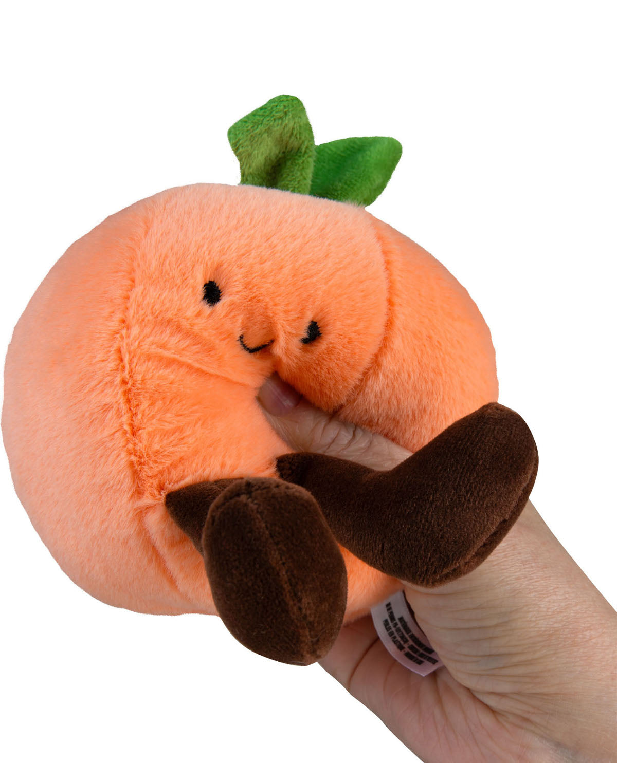 Plush pumpkin toy held in a hand on a white background