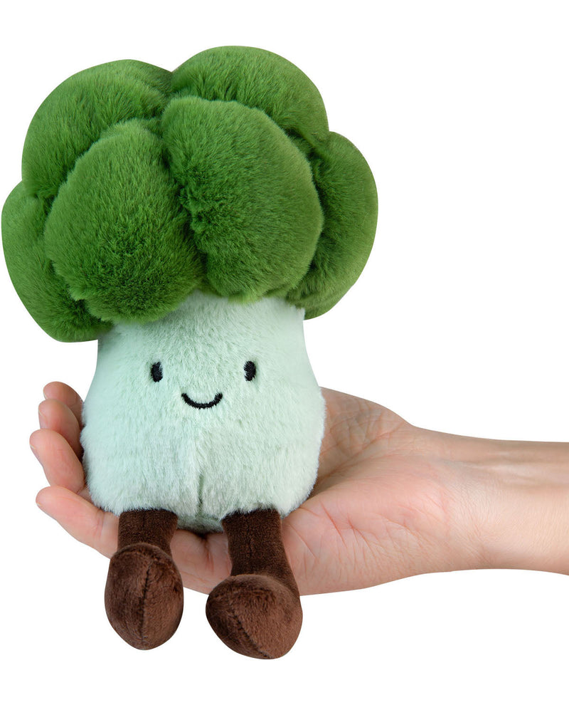 Plush toy resembling a broccoli with a smiling face held in a hand against a white background