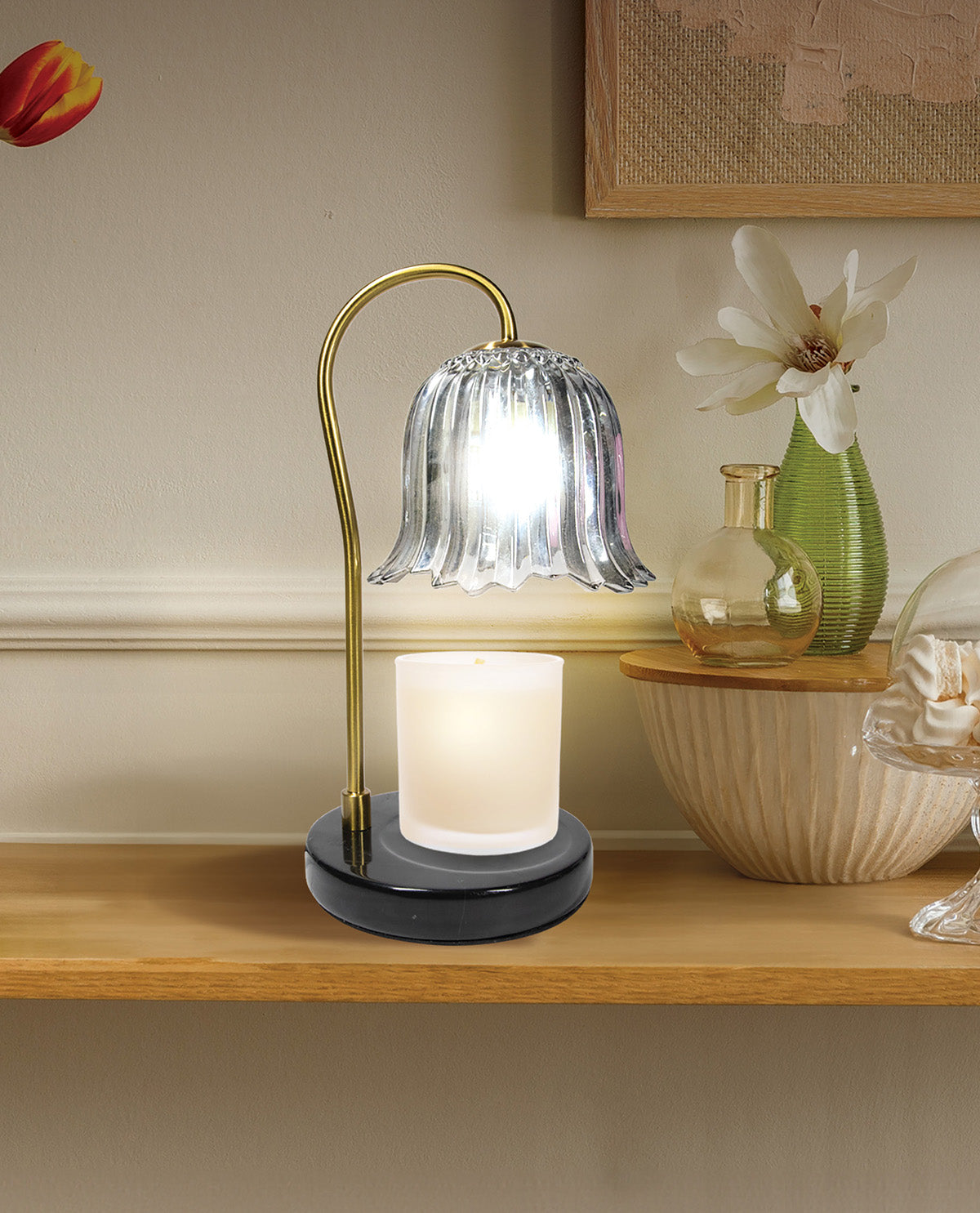 Decorative table lamp with a glass shade on a wooden surface, surrounded by flowers and decor items.