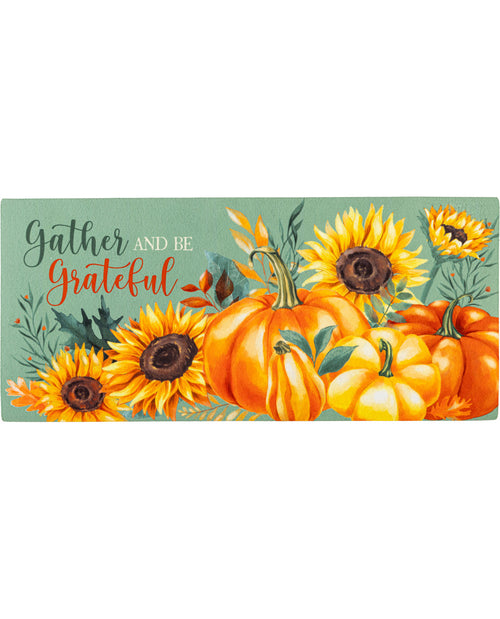 Decorative mat with pumpkins and sunflowers and text 'Gather and be grateful' on a green background