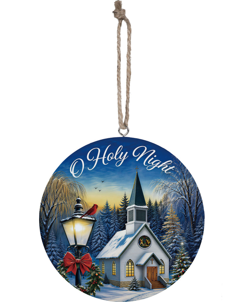 Round Christmas ornament featuring a winter village scene with a church, snow-covered trees, a lit streetlamp, and the words 'O Holy Night' in white script against a blue sky.