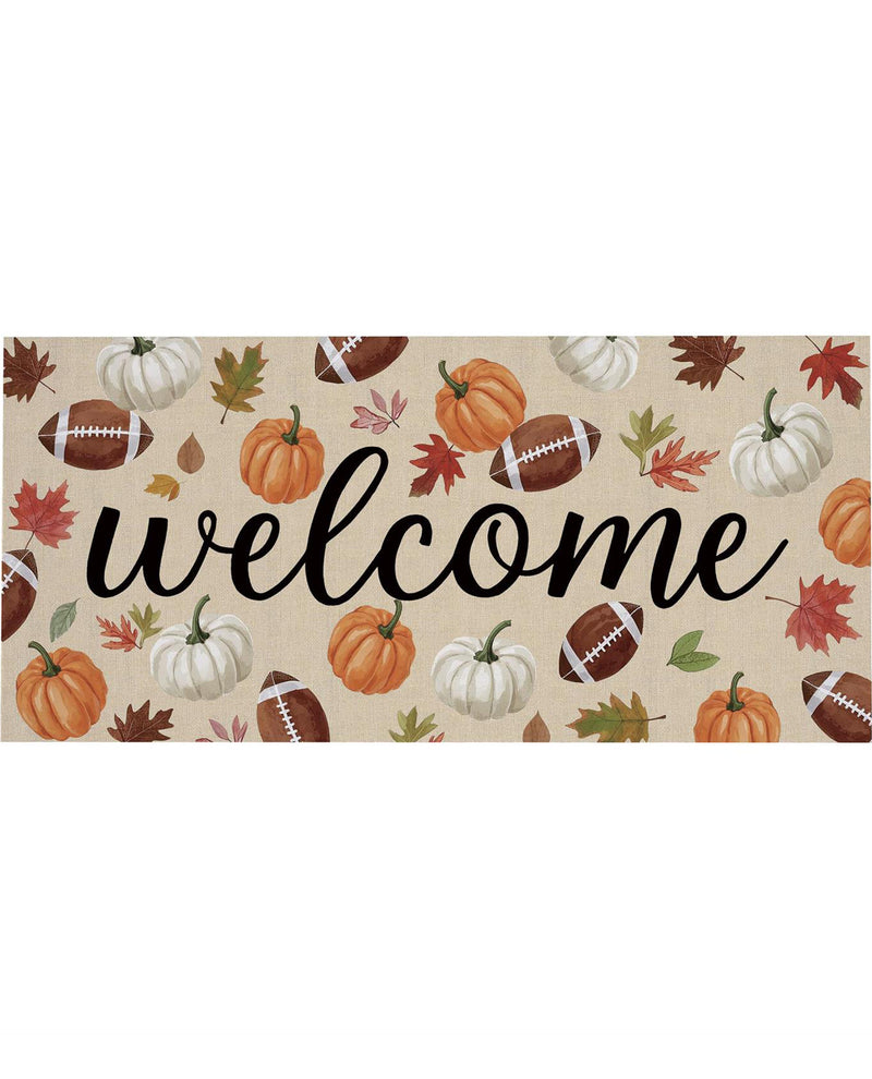 A rectangular autumn-themed doormat with a beige background, featuring the word 'welcome' in large black script. The mat is decorated with orange and white pumpkins, brown footballs, and red and green leaves.