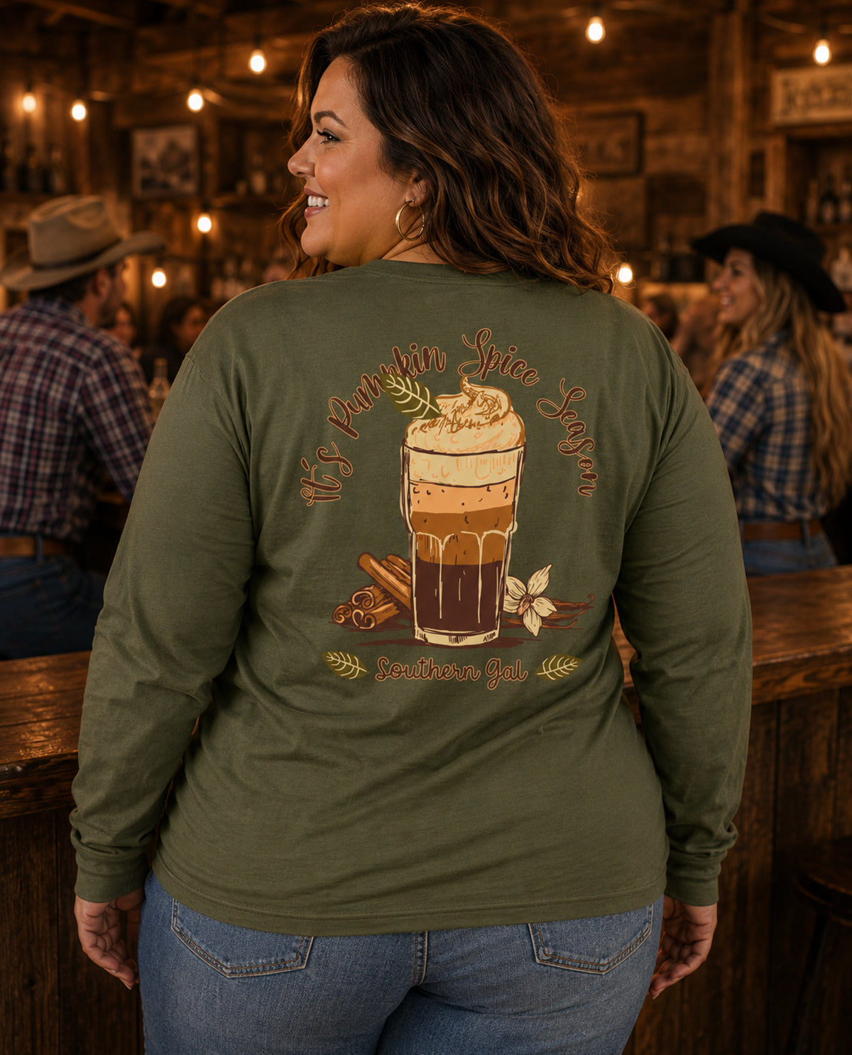 Woman wearing a green long-sleeve shirt with a coffee design in a rustic bar setting