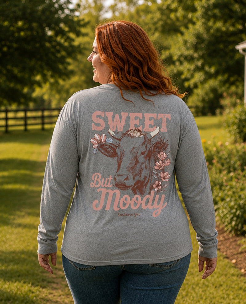 Woman wearing a gray long-sleeve shirt with a cow graphic and text in an outdoor setting