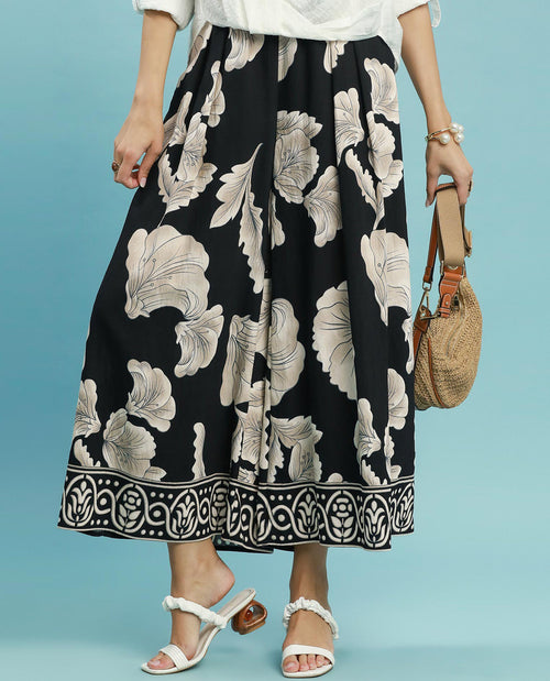 Person wearing a black floral patterned skirt on a blue background