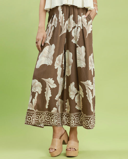 Person wearing a brown floral skirt on a green background