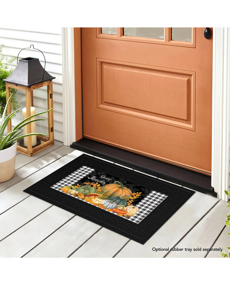 Decorative doormat with autumn design on a wooden floor in front of a door.