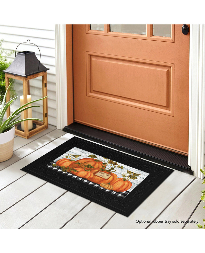 Decorative doormat with pumpkins on a wooden floor in front of a door.