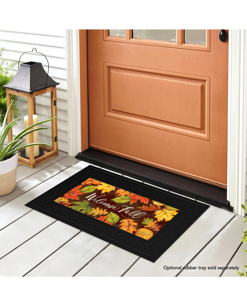 Decorative doormat with autumn design on a wooden floor in front of a door.