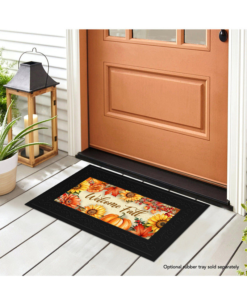 Decorative doormat with autumn design on a wooden floor in front of a door.