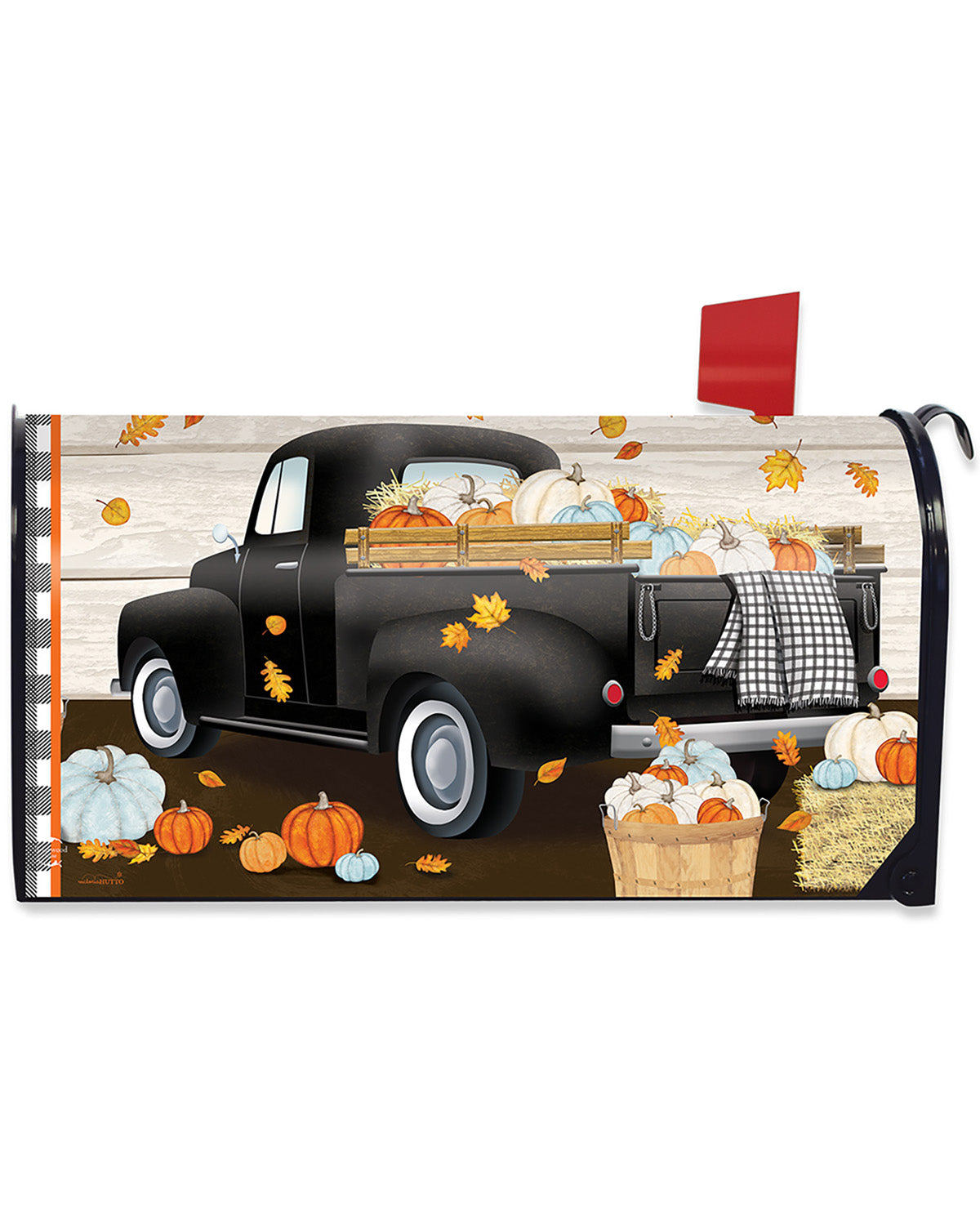 A decorative mailbox cover featuring a vintage black pickup truck loaded with pumpkins and gourds, with scattered autumn leaves, pumpkins, and a basket of produce on a rustic wood-plank background. A red flag is visible on the right side.
