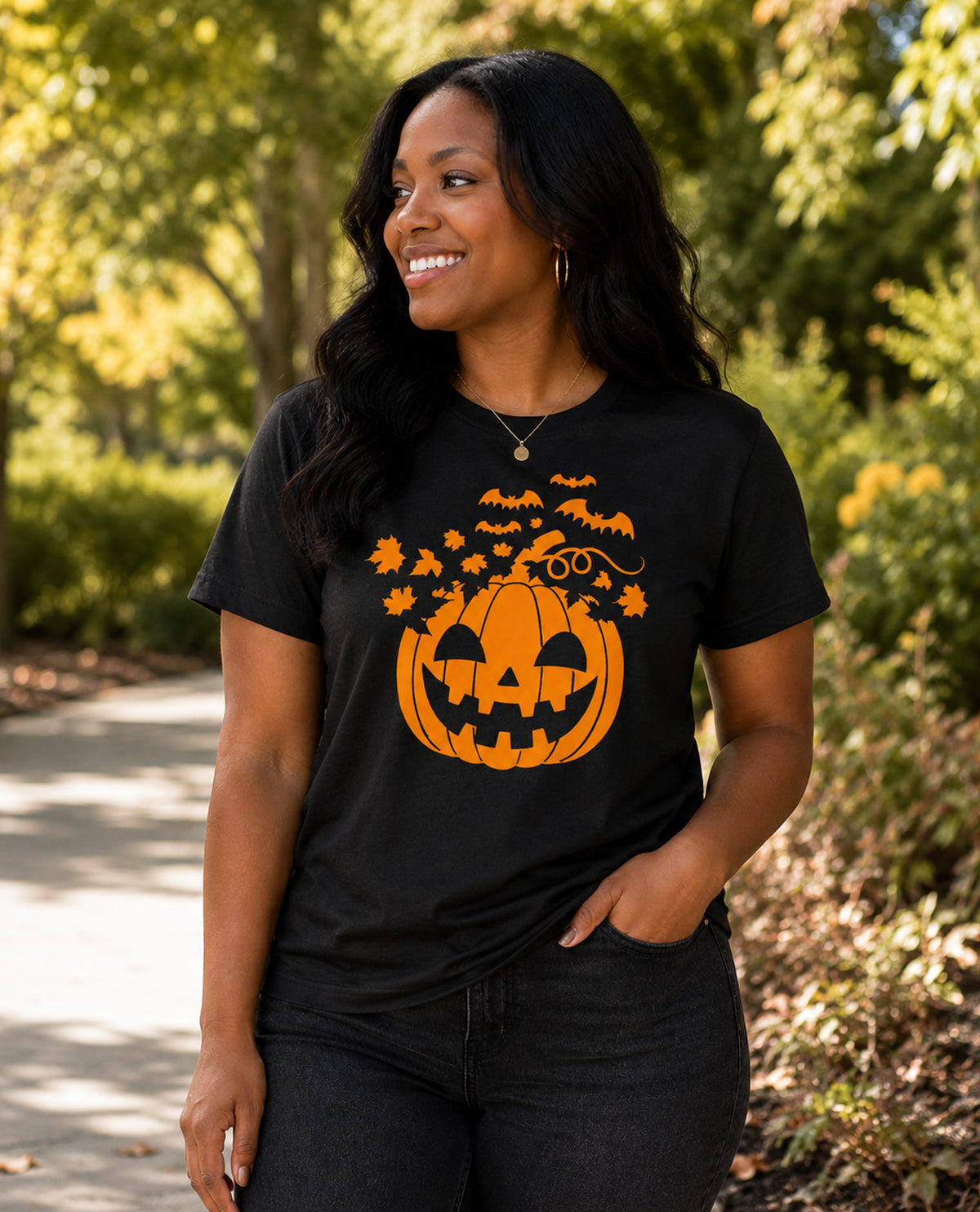 Woman wearing a black t-shirt with a Halloween-themed pumpkin design outdoors.
