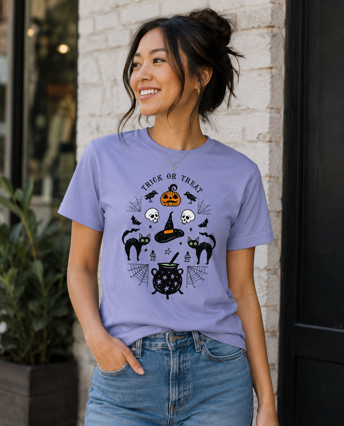 Woman wearing a purple Halloween-themed t-shirt with black graphics against a brick wall.