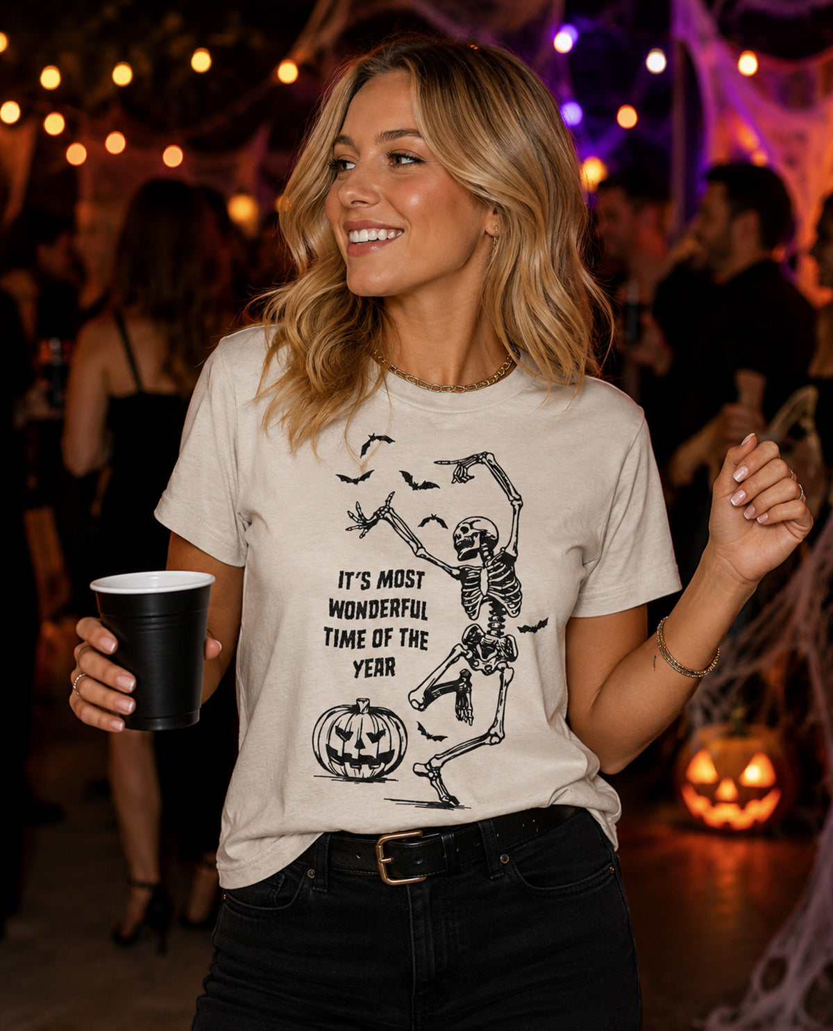 Woman wearing a Halloween-themed t-shirt with a skeleton design at a party.