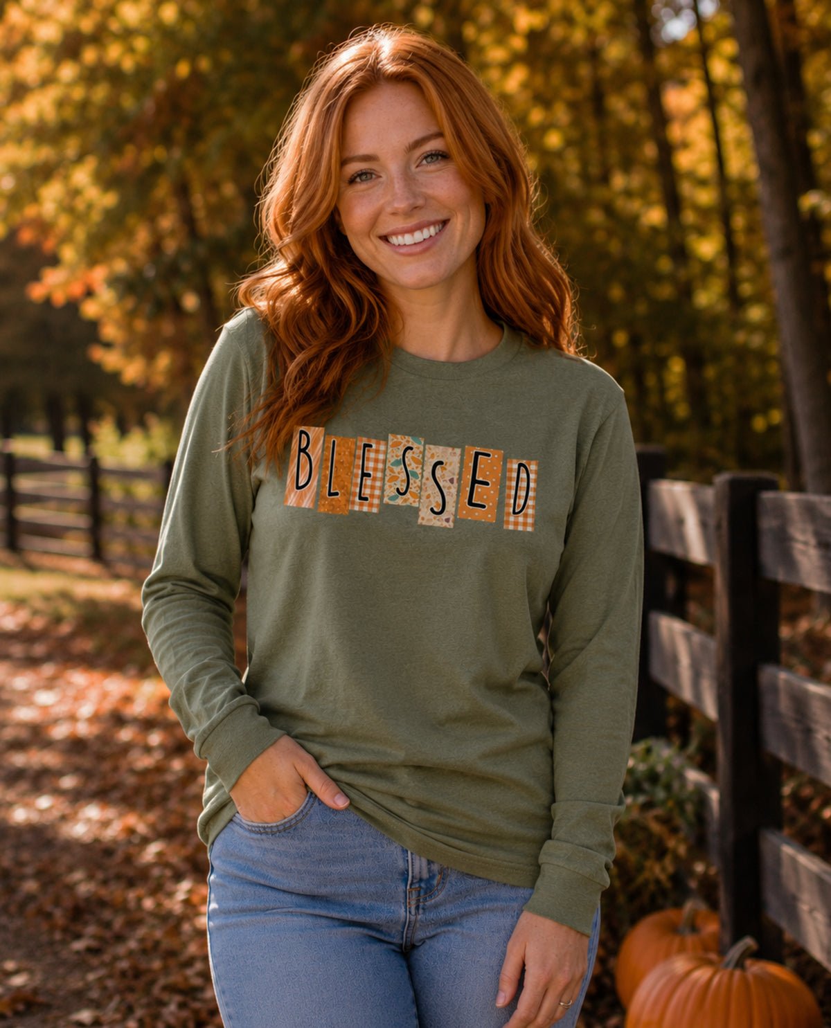 Woman wearing a green long-sleeve shirt with 'BLESSED' print, standing in an autumn setting.