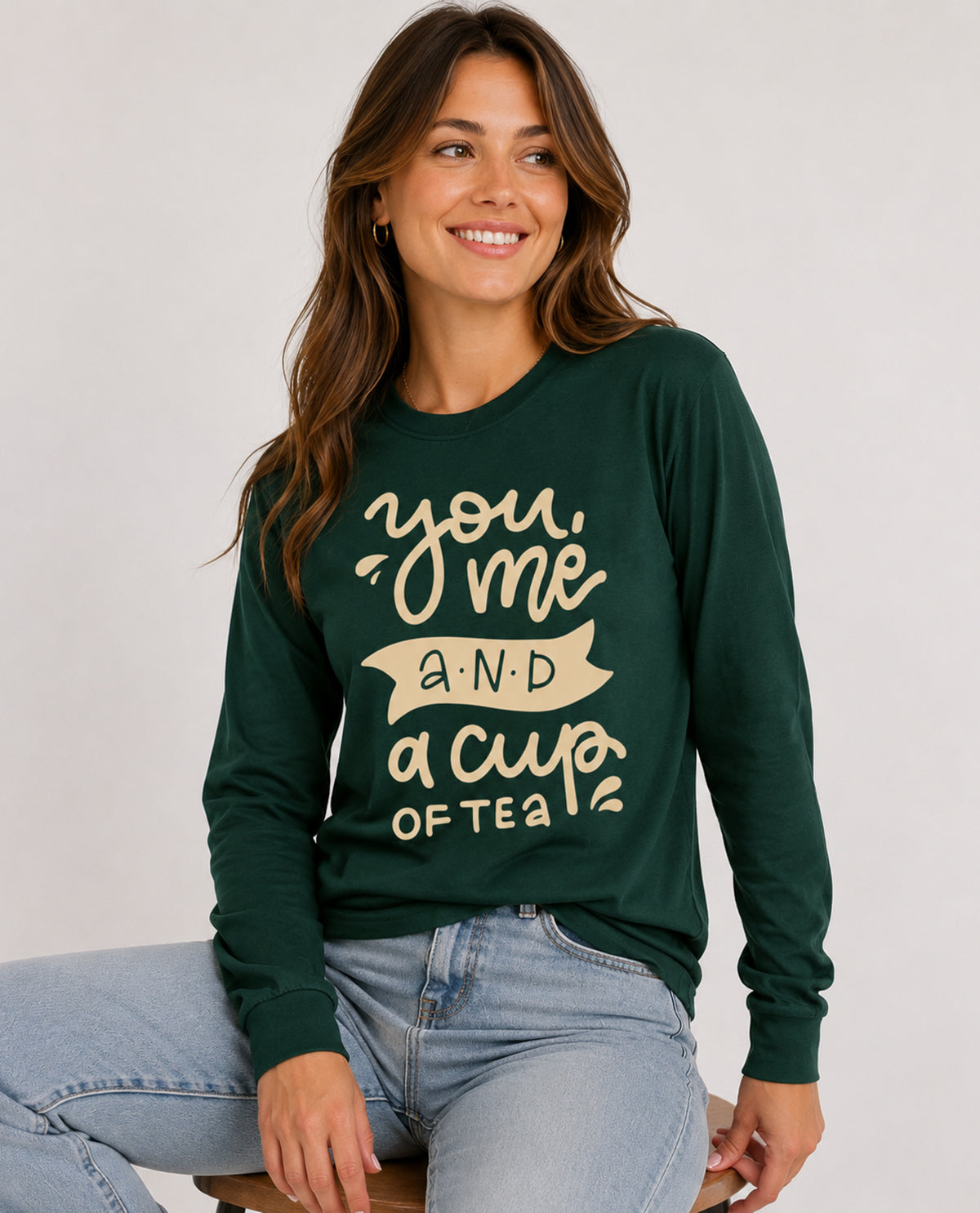 Woman wearing a green sweatshirt with text, sitting on a white background