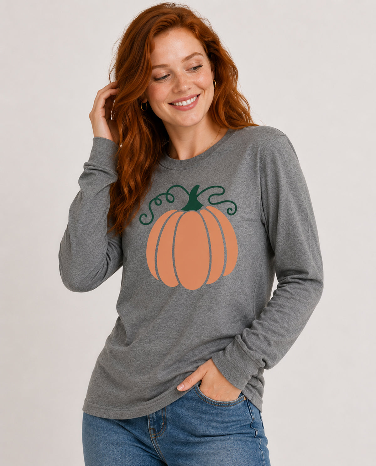 Woman wearing a gray long-sleeve shirt with a pumpkin design on a plain background