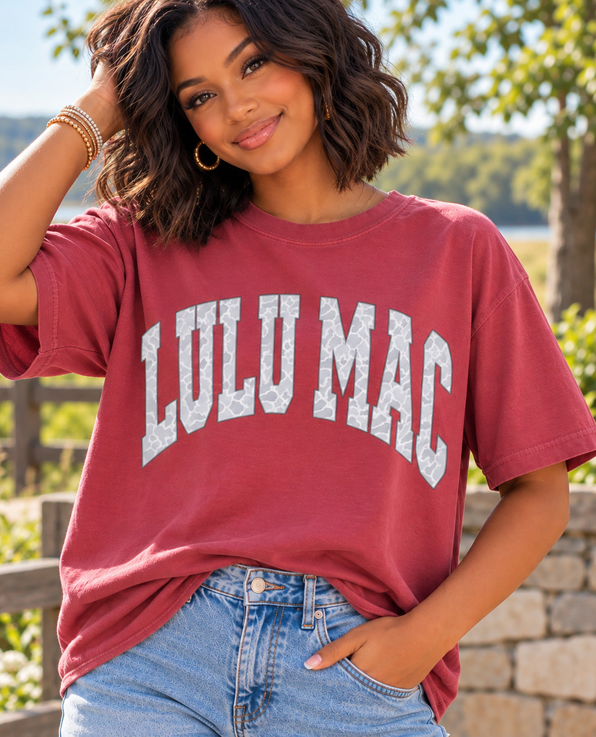 Missy model wearing a burgundy t-shirt with LULU MAC graphic with an outdoor background