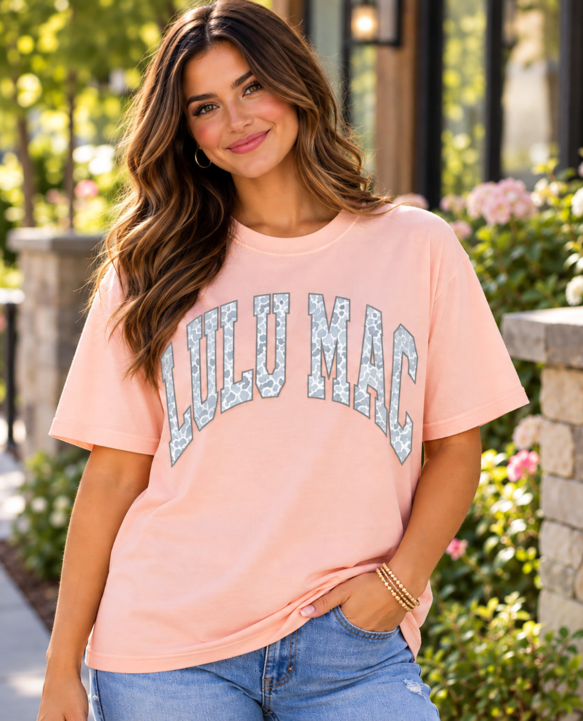 Missy model wearing a peach t-shirt with LULU MAC graphic with an outdoor background