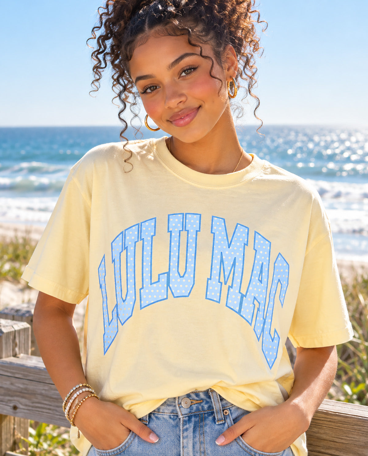 Missy model wearing a yellow t-shirt with LULU MAC design with an outdoor background