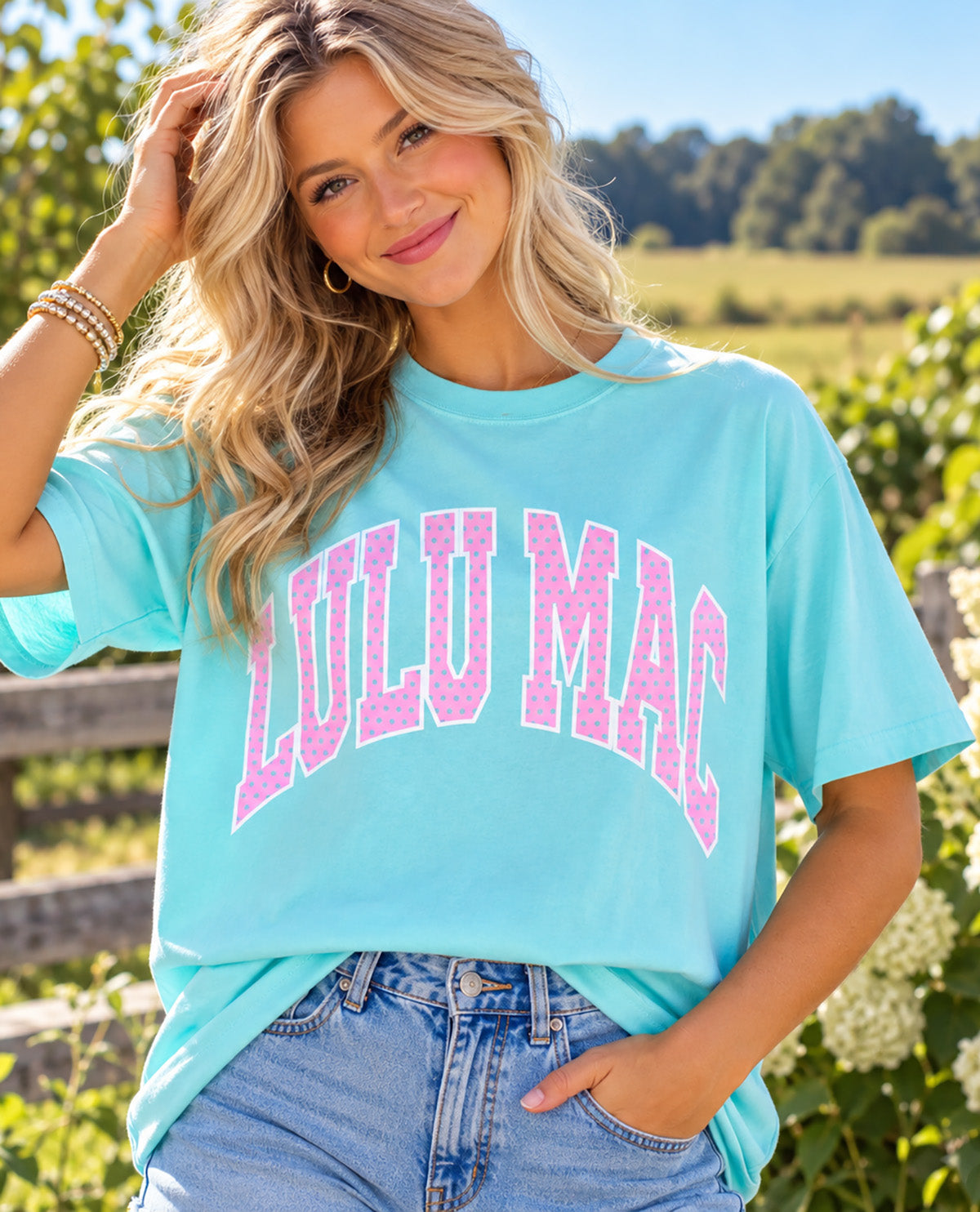 Missy model wearing a blue t-shirt with LULU MAC design with an outdoor background