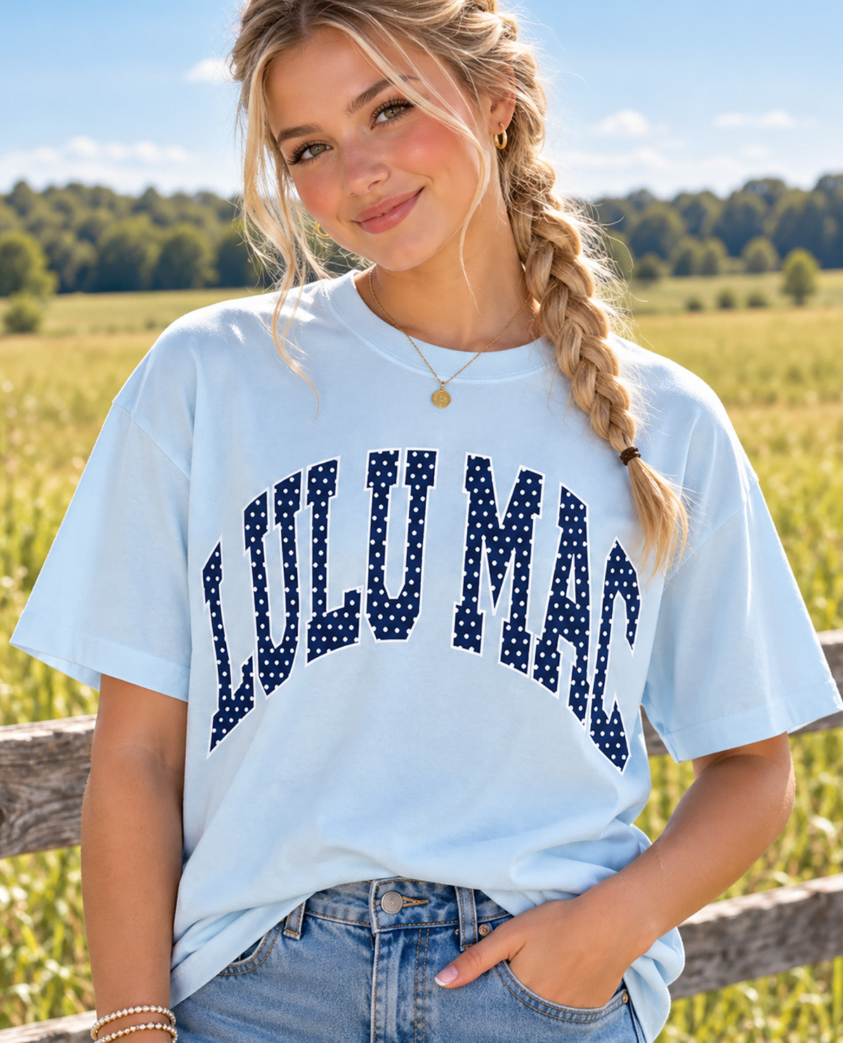 Missy model wearing a lt blue t-shirt with LULU MAC design with an outdoor background