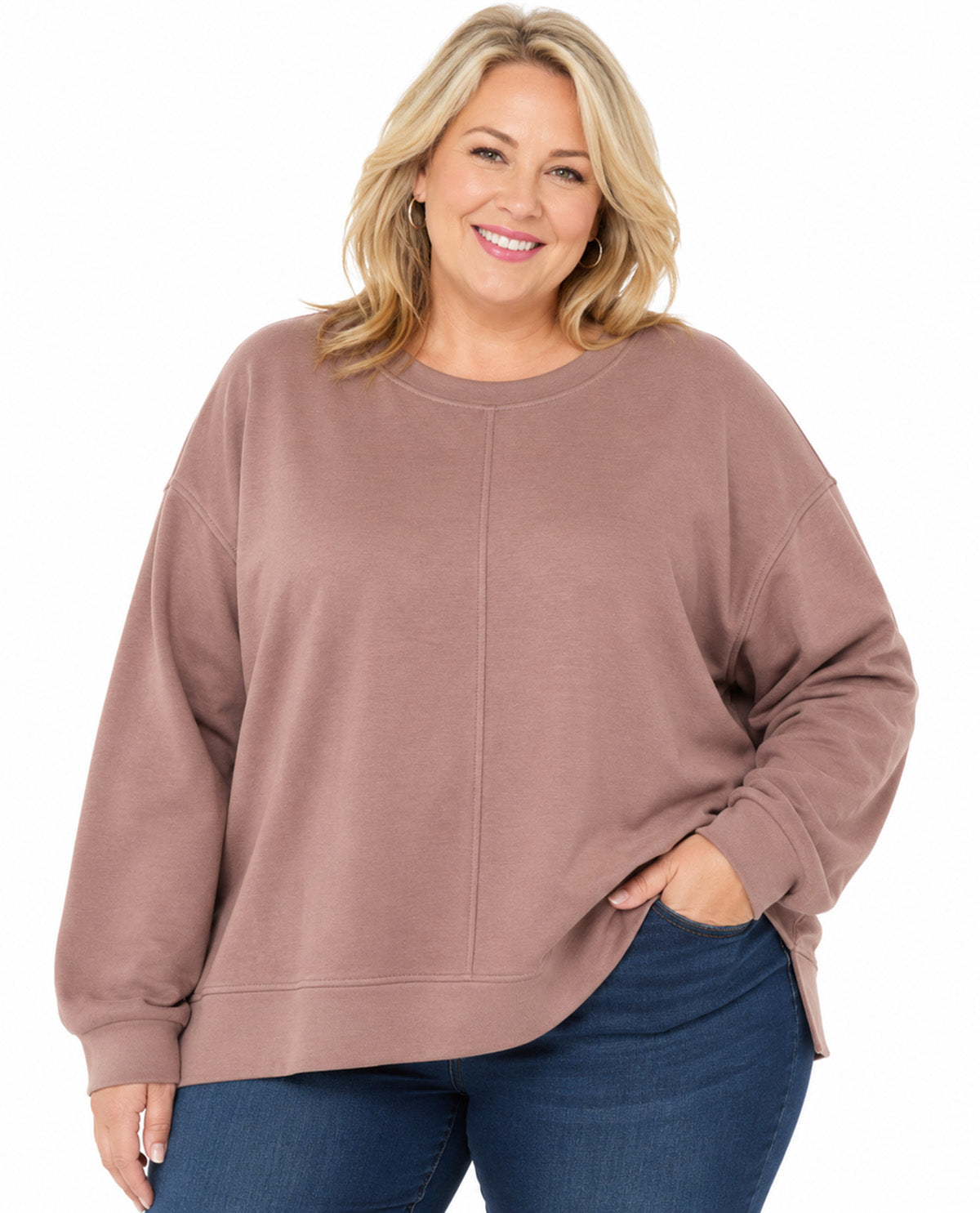 A woman wearing a dusty rose long-sleeve crewneck sweatshirt and blue jeans, standing against a plain white background.