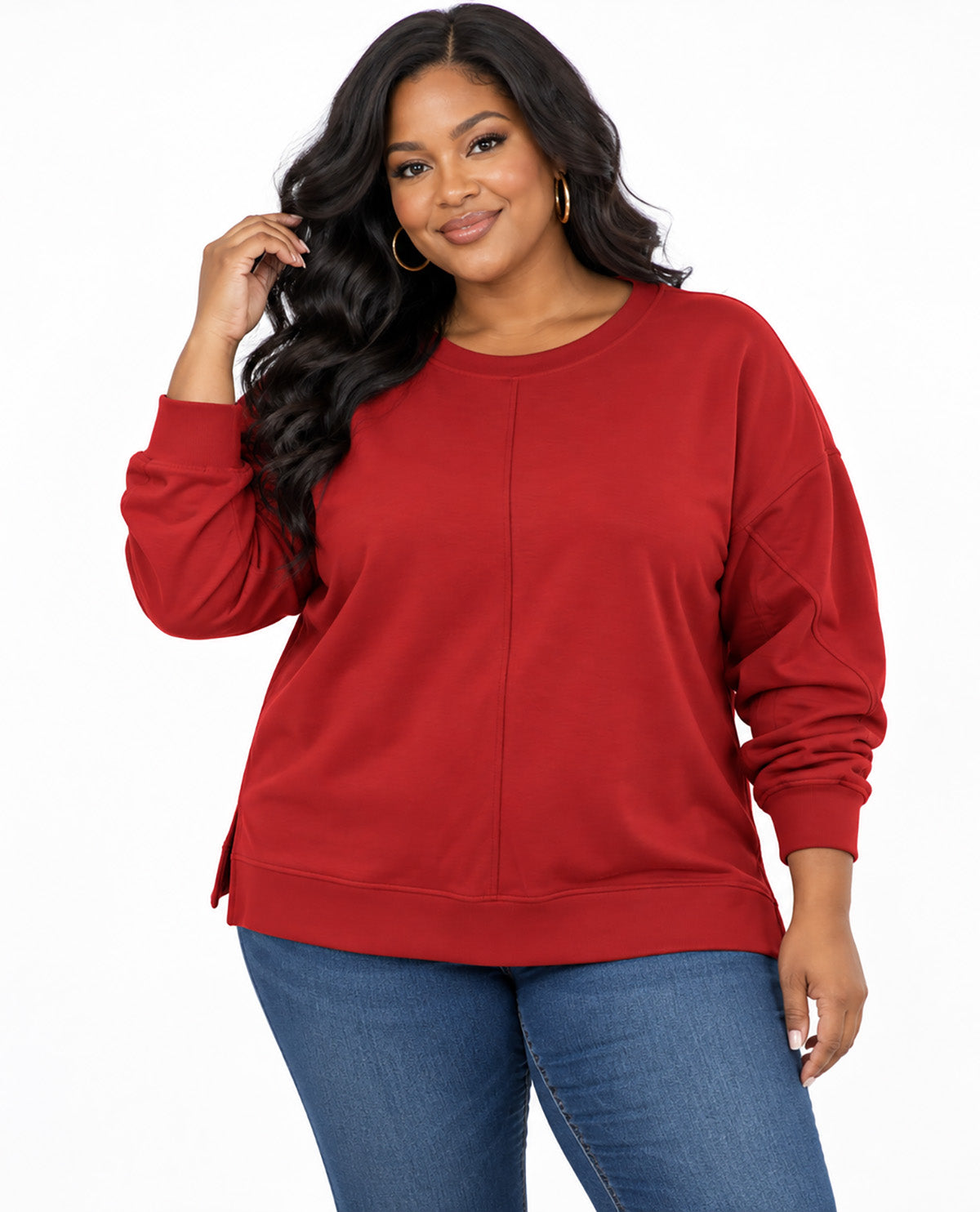 A woman modeling a red long-sleeve crewneck sweatshirt with a vertical seam detail down the front, paired with blue jeans, against a plain white background.