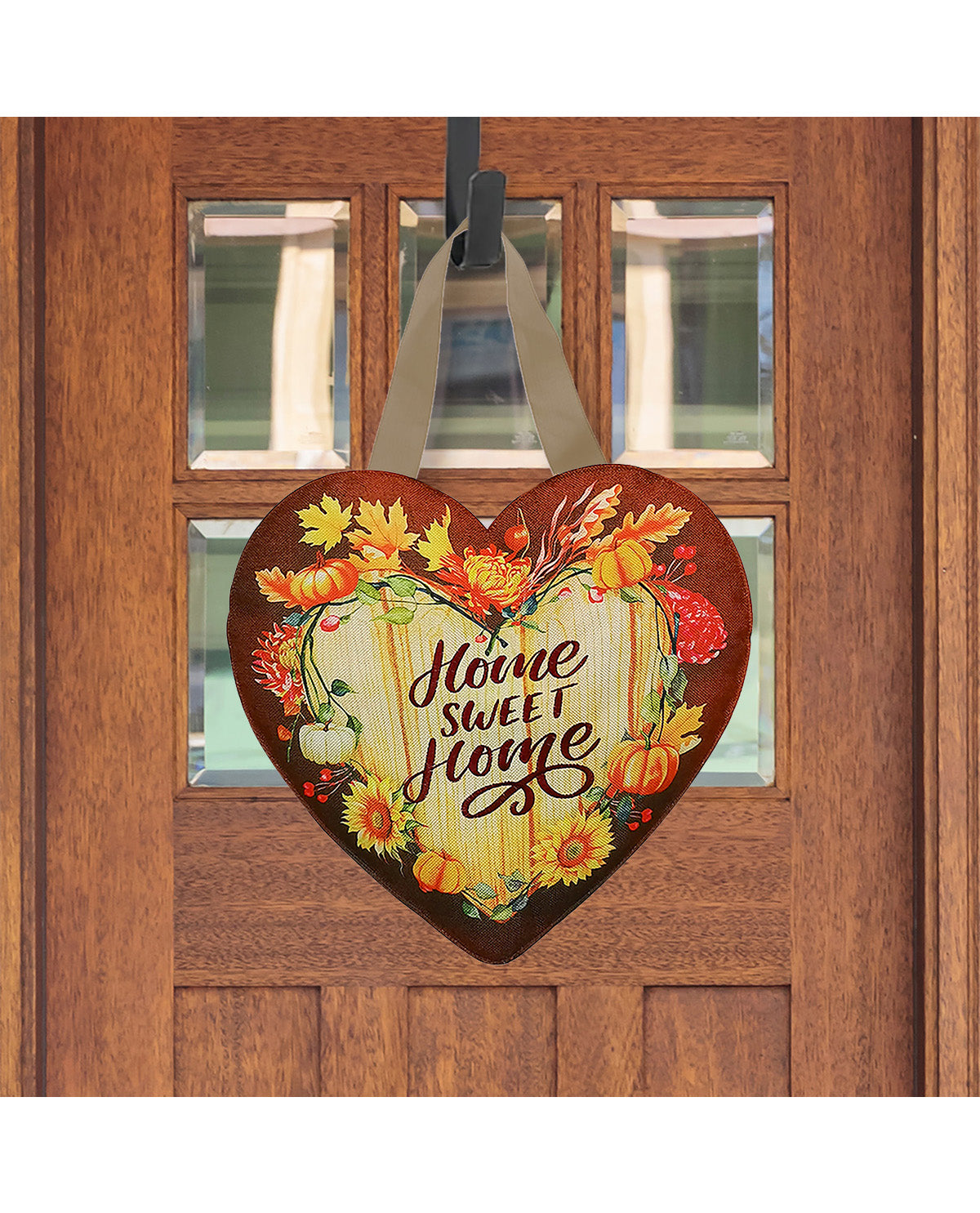 Decorative heart-shaped sign with 'Home Sweet Home' text and autumnal design hanging on a wooden door.
