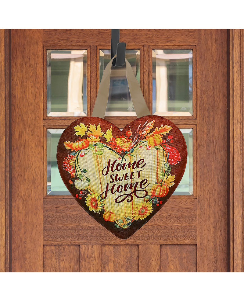 Decorative heart-shaped sign with 'Home Sweet Home' text and autumnal design hanging on a wooden door.