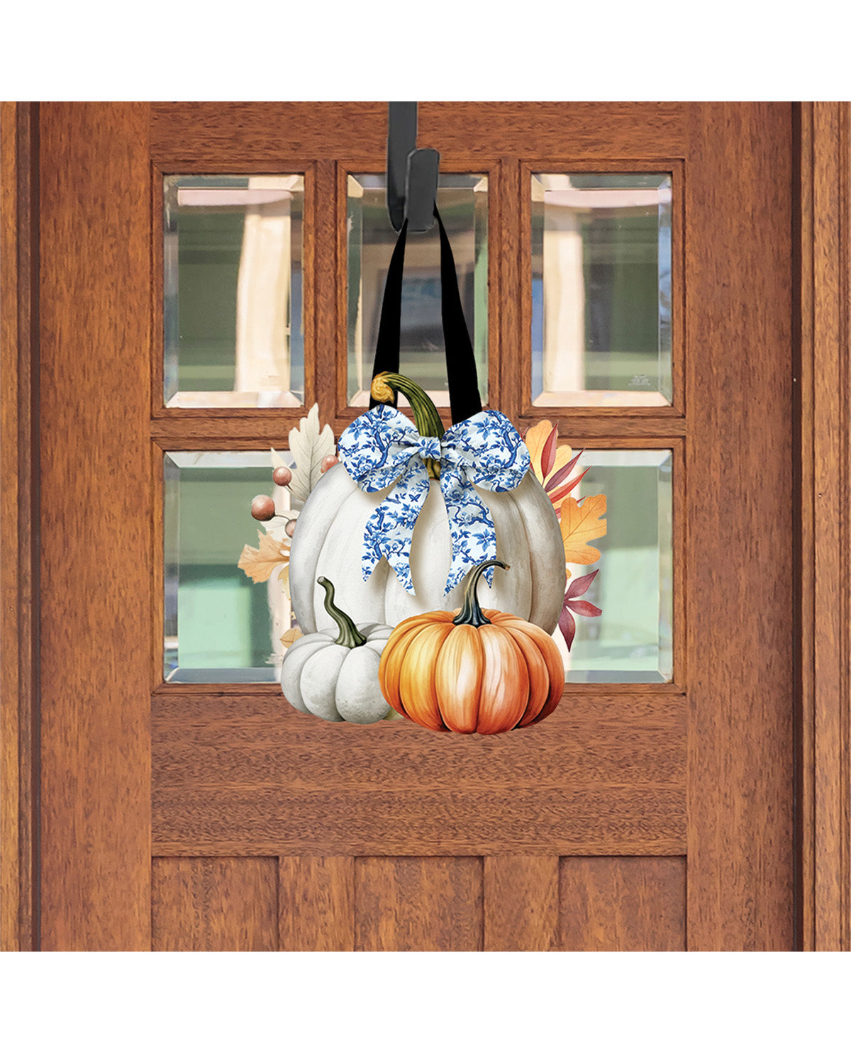 Decorative door hanger with pumpkins and flowers hanging on a wooden door.