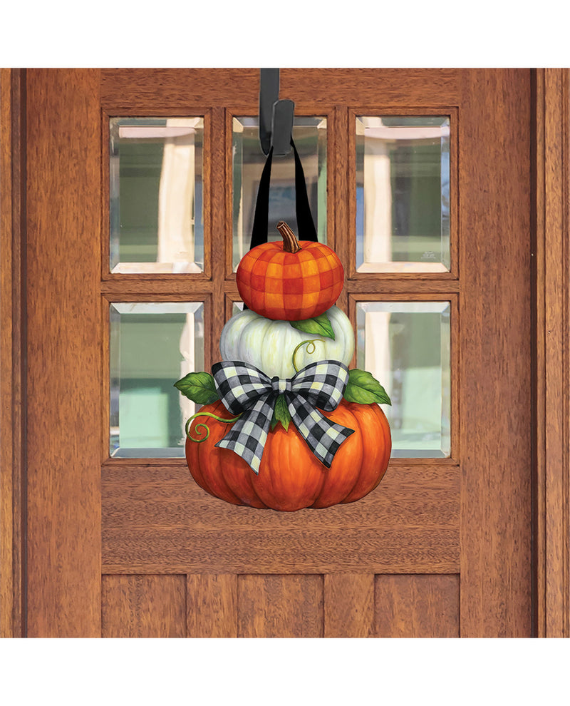 Decorative pumpkin door hanger with plaid bow on a wooden door