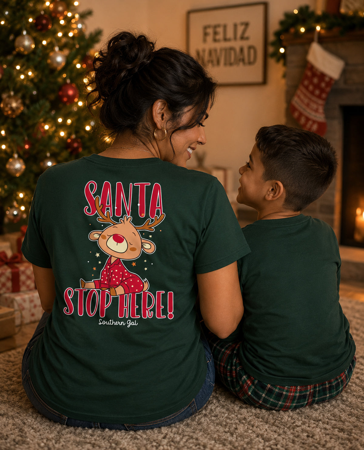 Two people wearing green t-shirts with a Christmas design in a festive room.
