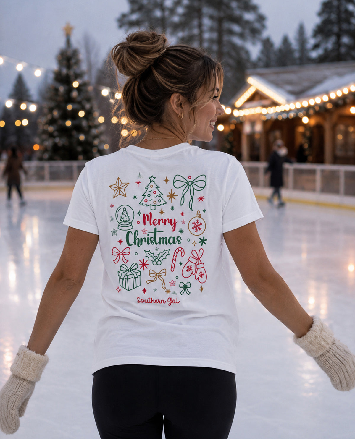 Woman wearing a white t-shirt with Christmas designs on an ice rink.