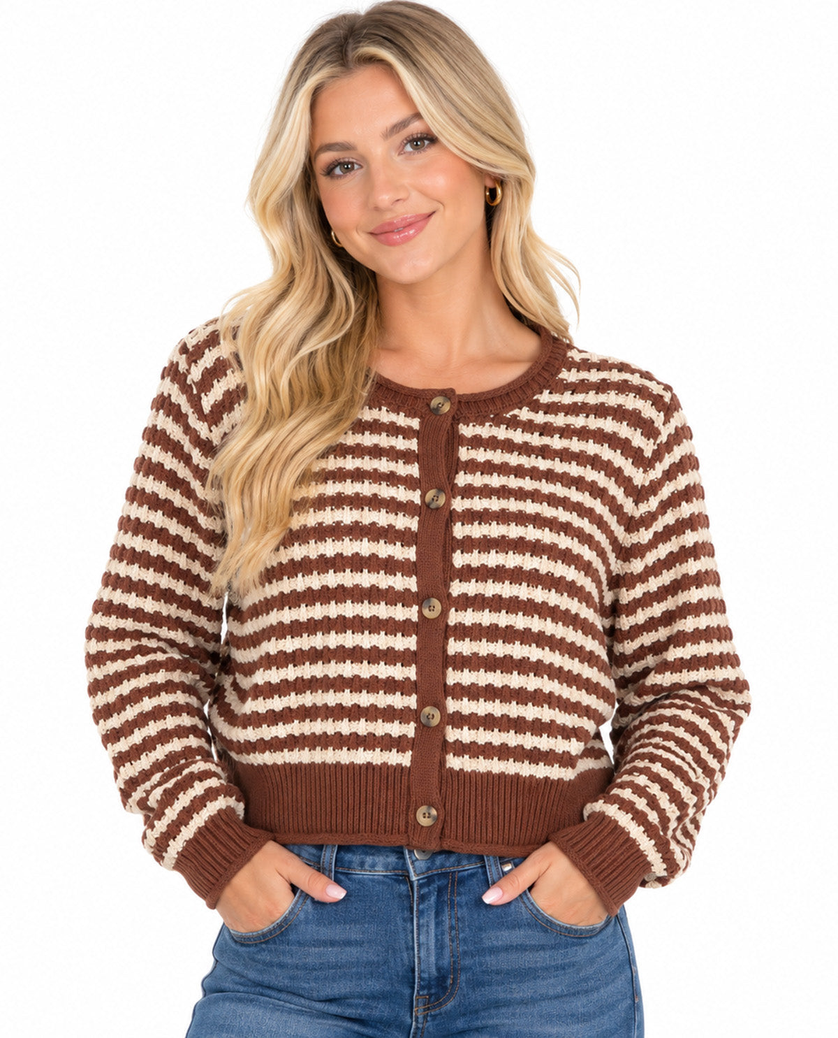 A woman wearing a brown and cream striped knit cardigan sweater with brown buttons, paired with blue jeans, against a plain white background.