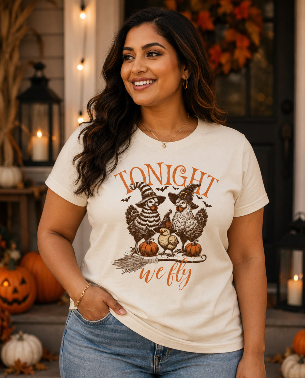 Woman wearing a white t-shirt with a Halloween-themed design in a decorated indoor setting.