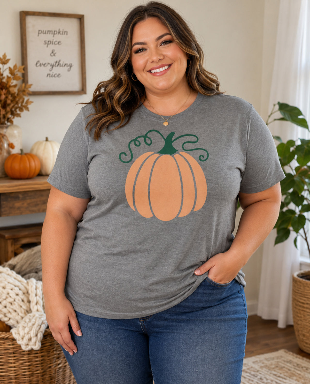 Woman wearing a gray t-shirt with a pumpkin graphic in a cozy indoor setting.