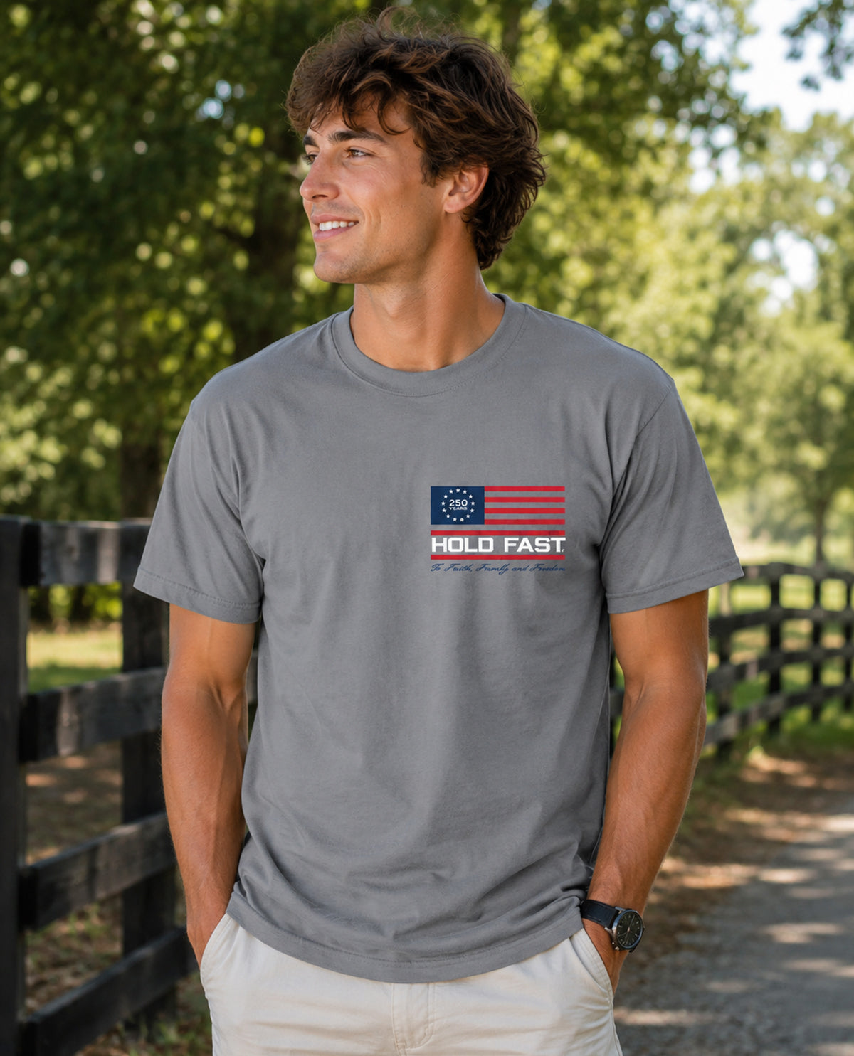 Man wearing a gray t-shirt with a logo and text outdoors