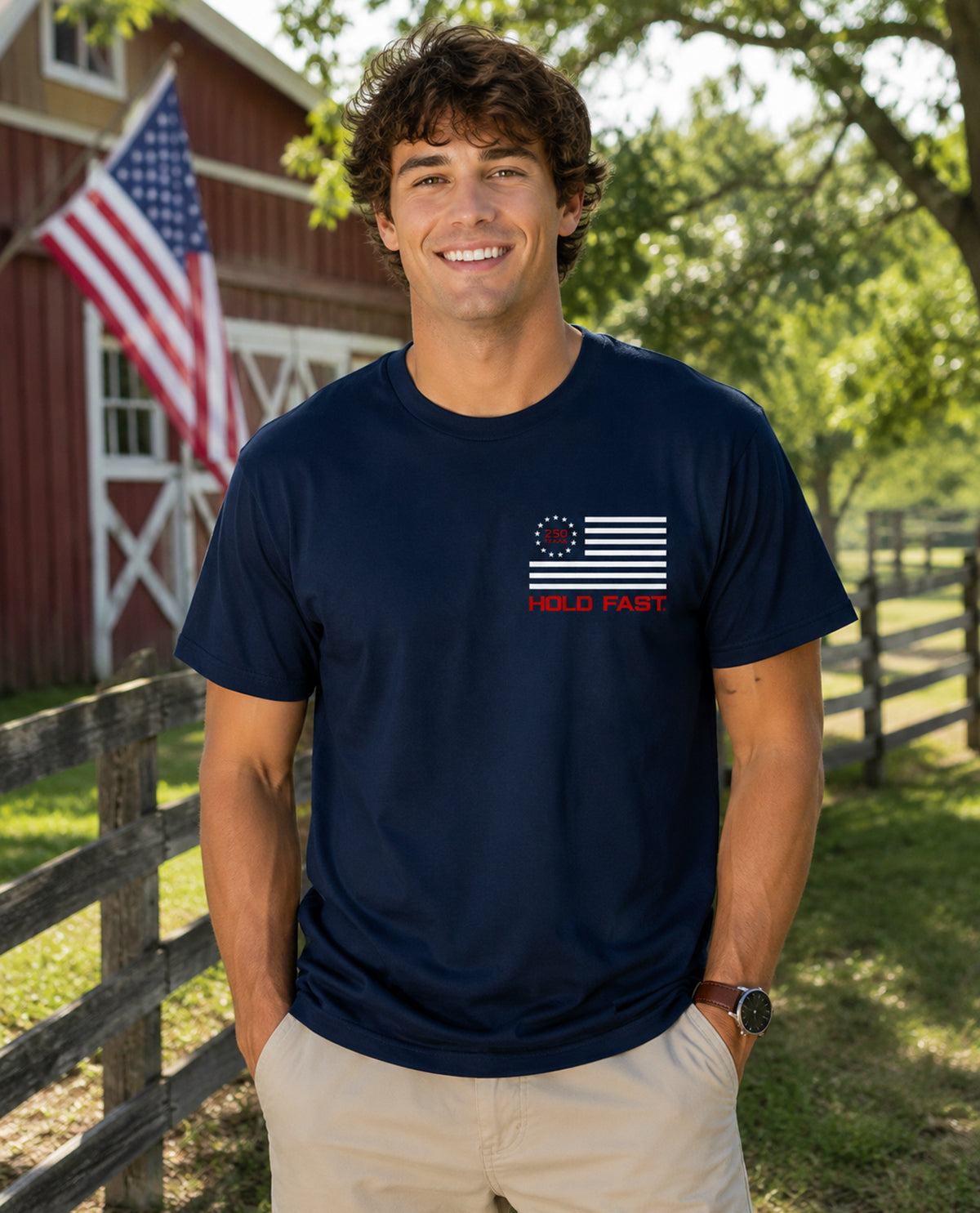 Man wearing a navy blue t-shirt with a flag design in front of a red barn and American flag.