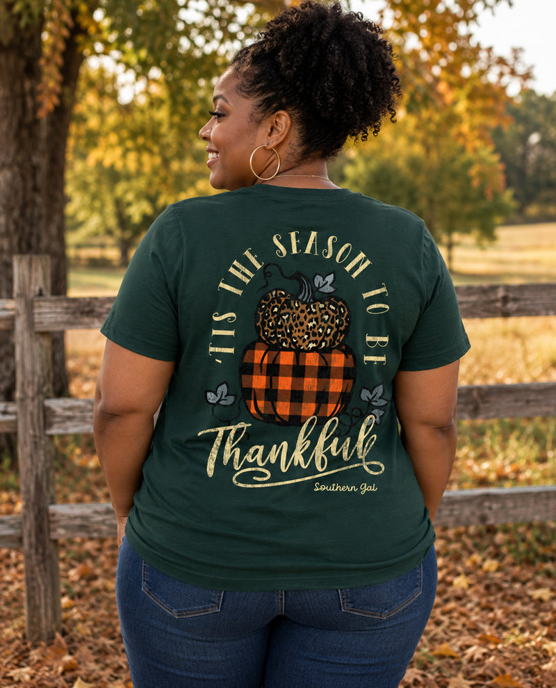 Woman wearing a green t-shirt with a fall-themed design in an outdoor setting.