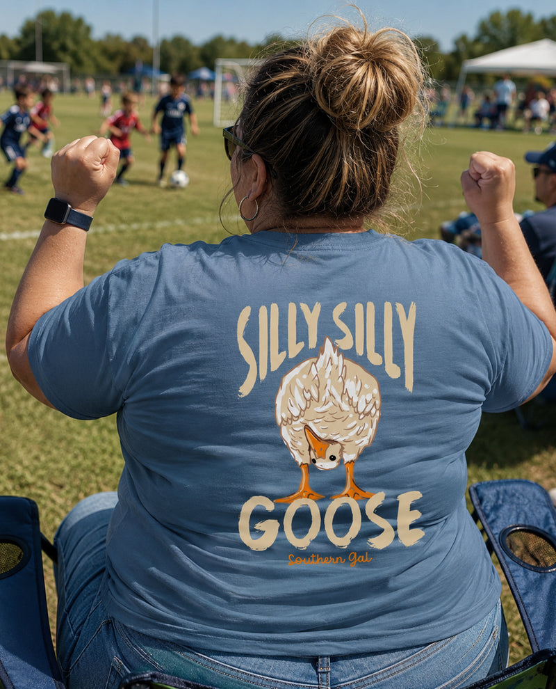 Person wearing a blue t-shirt with 'Silly Silly Goose' design on a sports field.