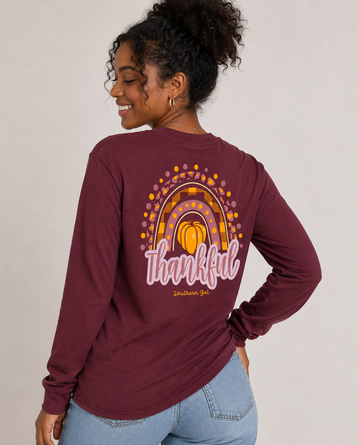 Woman wearing a maroon long-sleeve shirt with a colorful design and 'Thankful' text on the back.