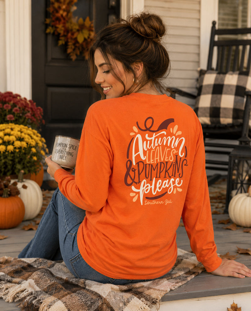 Woman wearing an orange shirt with 'Autumn Leaves & Pumpkin Please' text, sitting on a porch.