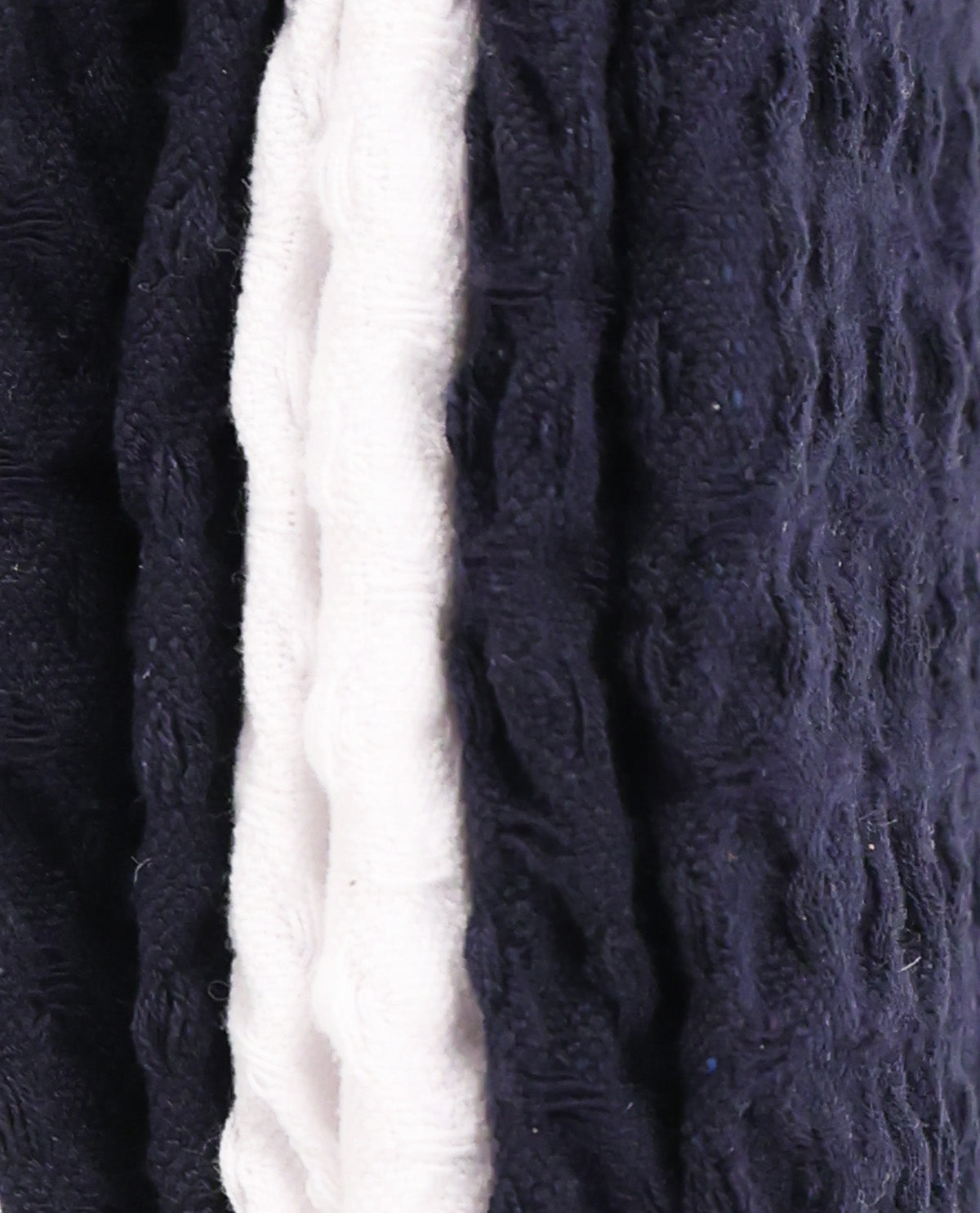 Close-up of a textured knit fabric with vertical stripes in dark navy blue and off-white.