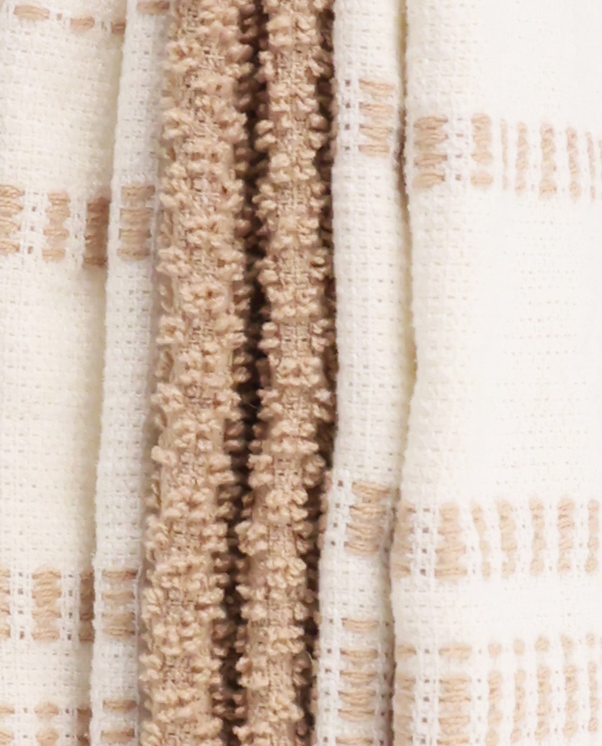 Close-up of a woven textile with vertical stripes in cream, beige, and light tan, showing textured knit and plush pile fabrics.