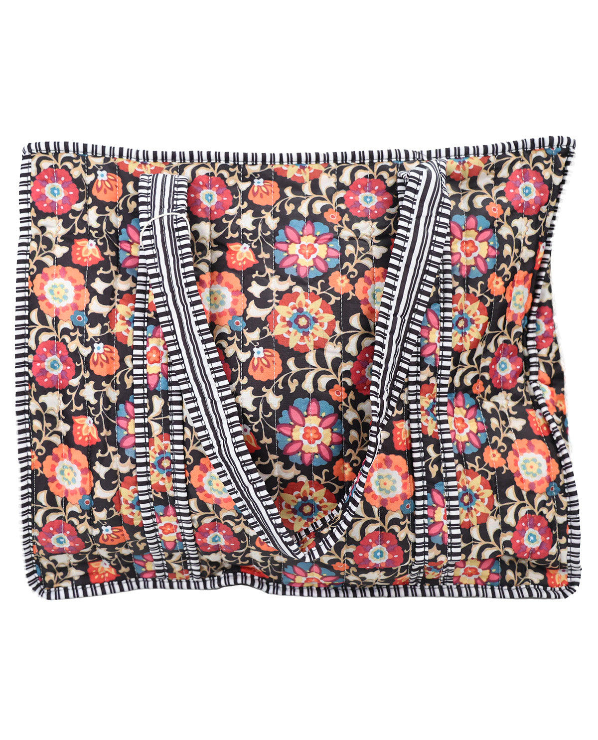 A square fabric tote bag with a dense floral and paisley print on a black background, featuring cream-colored shoulder straps with black stripes and a black-and-white fringed edge.