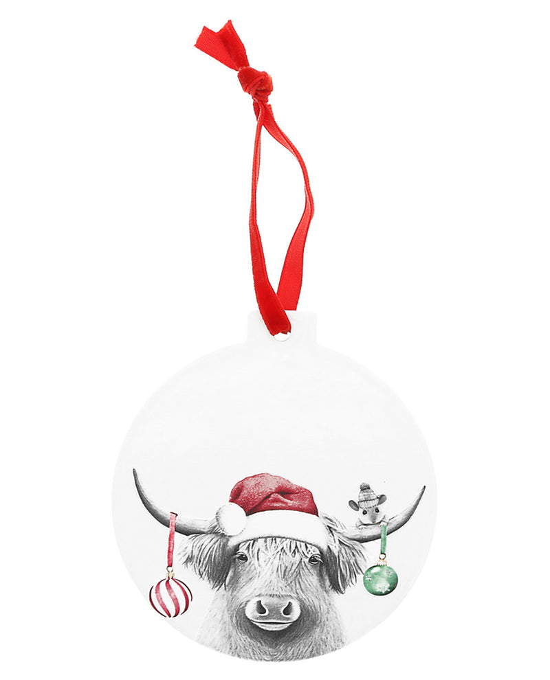 Round Christmas ornament with a black and white cow wearing a Santa hat, red ribbon, and colorful ornaments on a white background.