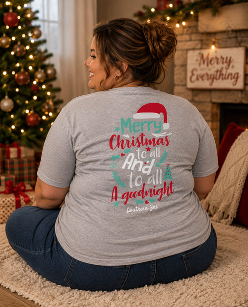 Woman wearing a Christmas-themed t-shirt with decorative text in a festive setting.