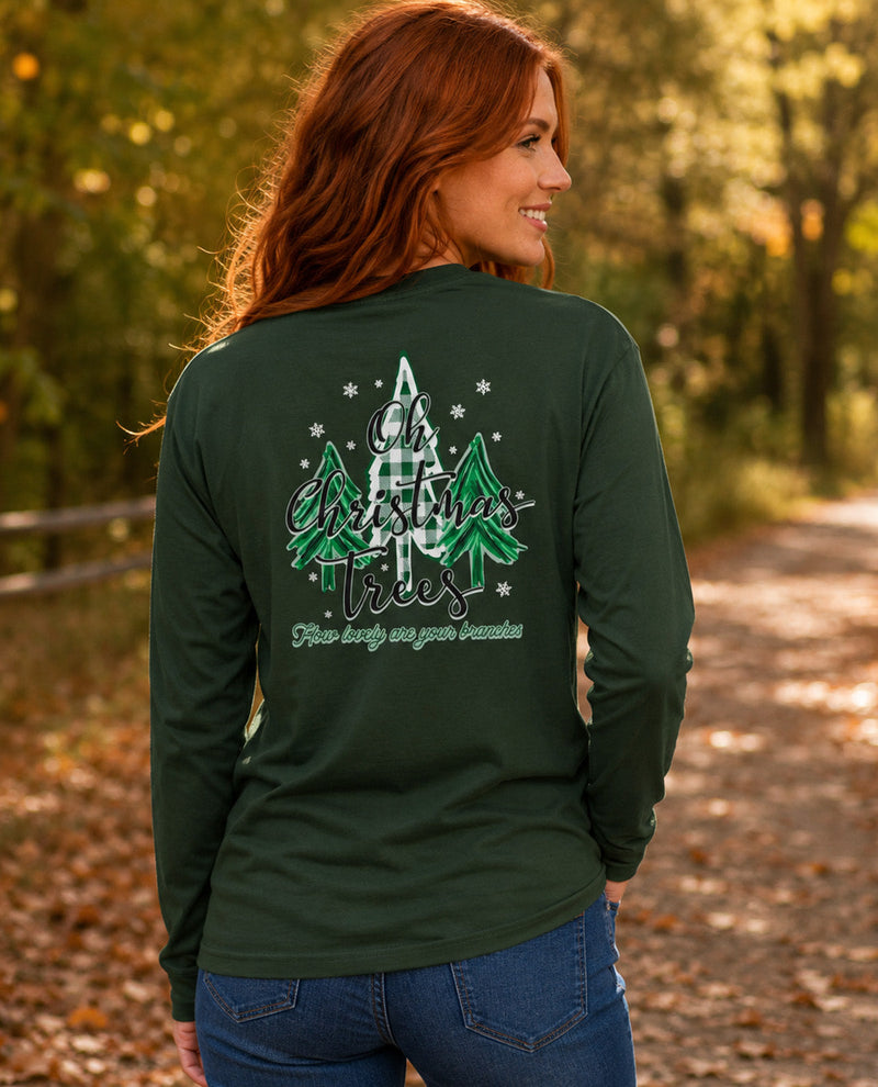 A woman with red hair is shown from behind wearing a dark forest green long-sleeve shirt with a graphic on the back. The graphic features green and white plaid Christmas trees, white snowflakes, and the text 'Oh Christmas Trees' .